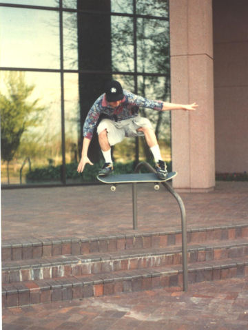 Mark Johnston nose-slide tail-grab on a nearby rail
